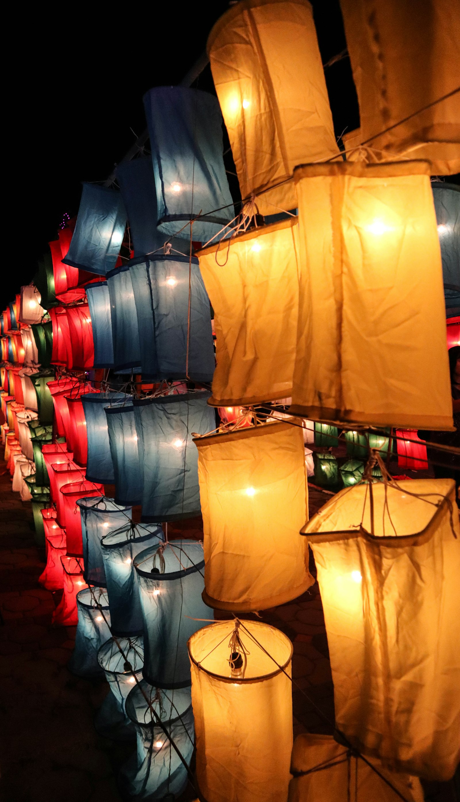 Glowing lanterns floating upward into a dark sky